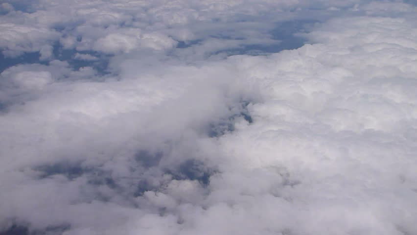 Flying over Pacific Northwest with clouds below and blue sky atmosphere.