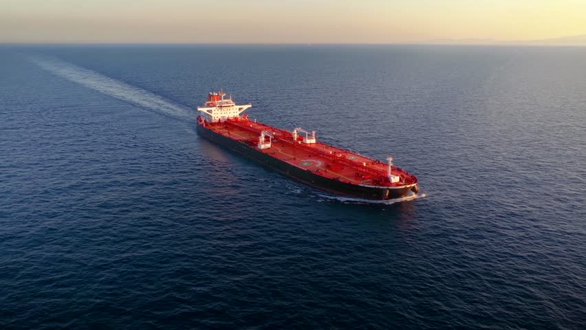 Aerial view of a heavy loaded crude oil or chemical goods tanker ship sailing over the ocean during sunset time