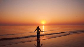 Young woman raising hands on beach during sunset at Mandvi, Gujarat, India. Summer holidays at tropical island. Small waves crashing on shore and sun setting on horizon. Relaxation concept  - Powered by Shutterstock - Get 15% off with code: PIKWIZARD15