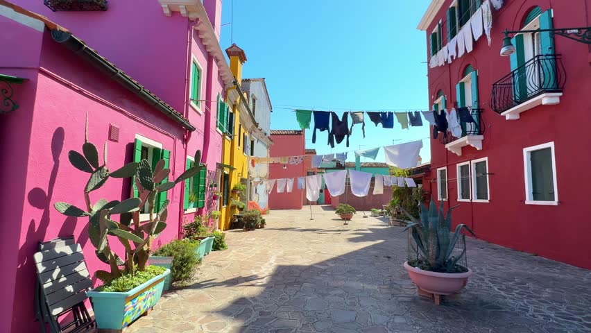 Colorful architecture in Burano island, Venice, Italy. Red and pink facades of the houses. Colorful laundry is drying outside. Famous travel destination
