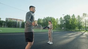 Boxer jumping using skipping rope. Woman is putting on boxer gloves. Man and woman warming up for box training at sports ground. Boxer routine. 4K, UHD - Powered by Shutterstock - Get 15% off with code: PIKWIZARD15