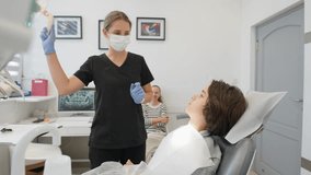 An orthodontist provides consultation for a teen patient about bite correction. The doctor examines teeth before installing braces or a removable aligner, which is visible on the table nearby. - Powered by Shutterstock - Get 15% off with code: PIKWIZARD15