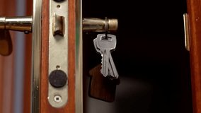 House keys hanging on an old door handle with golden lock. Wooden brown keyring in the shape of building - Powered by Shutterstock - Get 15% off with code: PIKWIZARD15