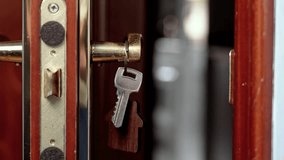 Apartment keys with wooden house-shaped keychain hanging on golden door handle against room background. Close-up - Powered by Shutterstock - Get 15% off with code: PIKWIZARD15