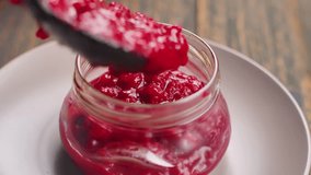 A close-up shot. A spoon carefully pours thick, homemade cranberry sauce into a clean glass jar. The process of canning and preserving fresh holiday jam for storage - Powered by Shutterstock - Get 15% off with code: PIKWIZARD15
