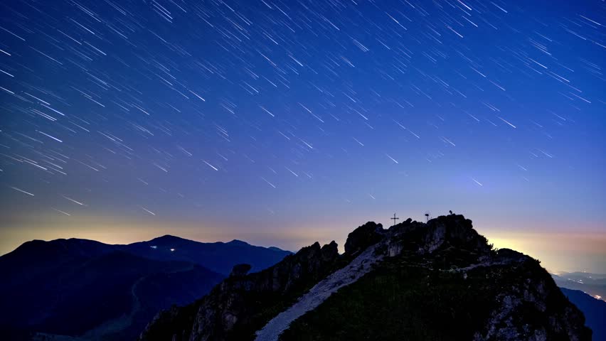 Timelapse of star trails and mountain landscape at night from a peak, moonlight