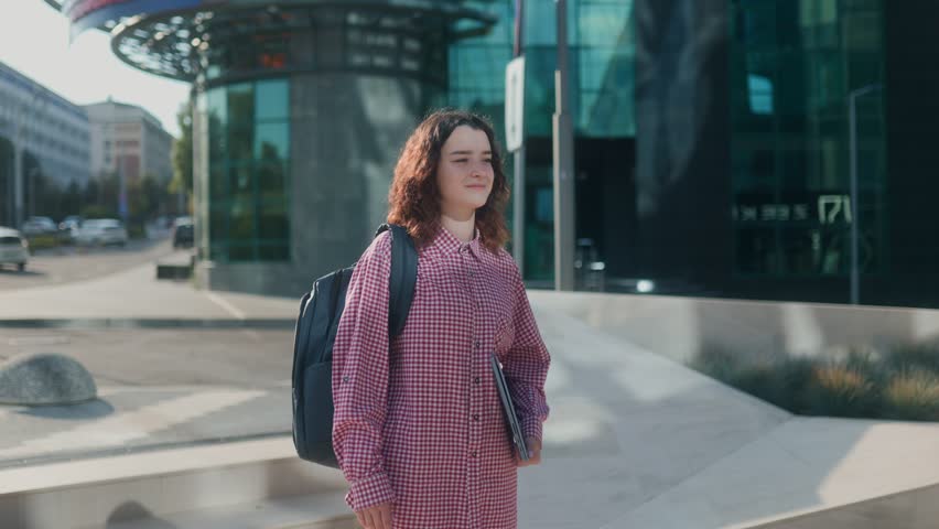 Two cheerful students laugh and greet each other outdoors on the university campus, expressing joy, energy, and the lively spirit of student friendship.