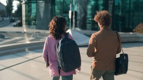 Two students, male and female, walk side by side on a university campus. Rear view shows backpacks and casual outfits, reflecting a friendly college lifestyle. - Powered by Shutterstock - Get 15% off with code: PIKWIZARD15
