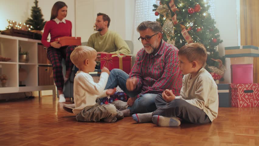 Multigenerational family sharing christmas gifts near sparkling tree, expressing joy and excitement during festive holiday gathering at home
