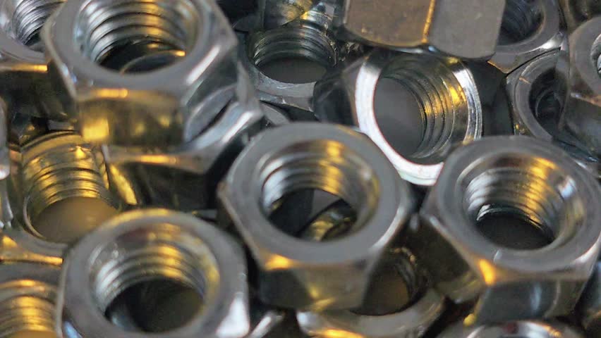 A close-up video showcases a pile of shiny metal nuts. The camera focuses on the details of the fasteners, highlighting their texture and metallic sheen.