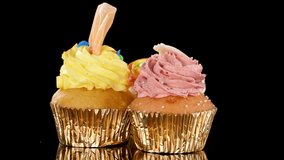 Three colorful cupcakes with sprinkles rotate on a black background under bright studio lighting. - Powered by Shutterstock - Get 15% off with code: PIKWIZARD15