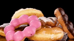 Hand picking pink glazed donut from assorted stack on reflective surface under bright studio lighting. - Powered by Shutterstock - Get 15% off with code: PIKWIZARD15
