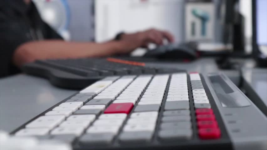 A close-up, low-angle shot of a gray keyboard with a red escape key and red function keys, with a person