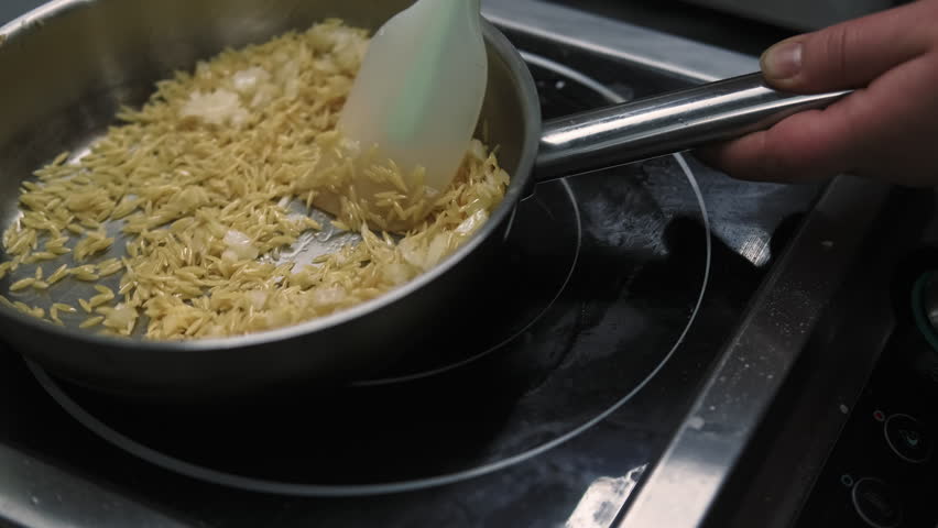 Stirring rice. Cooking asian food. Chef hand adding oil on hot metal frying pan mixing meal by spatula. Traditional oriental cuisine.