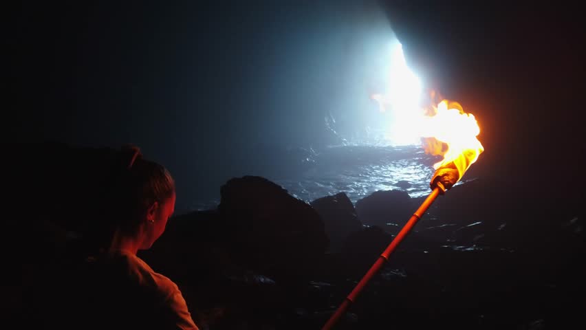 Tourist exploring dark Guincho cave with burning torch in Gran Canaria, Spain