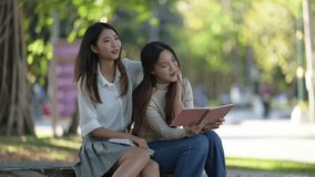 Two women sitting on a bench, one reading a book. Scene is peaceful and relaxing - Powered by Shutterstock - Get 15% off with code: PIKWIZARD15