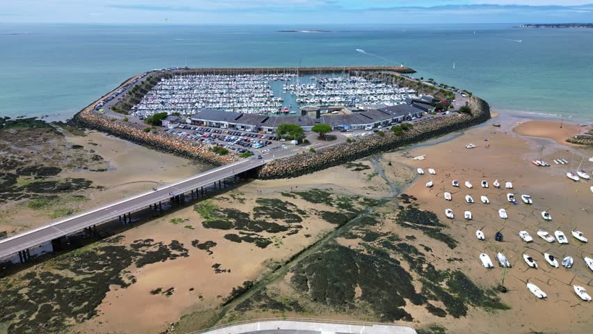 Pornichet Marina at low tide, sailboats, bridge, and boats on sandy beach, France. Aerial forward