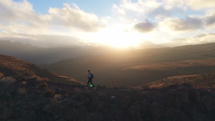 Aerial view over Woman hiking on mountain ridge at sunset in Gran Canaria
