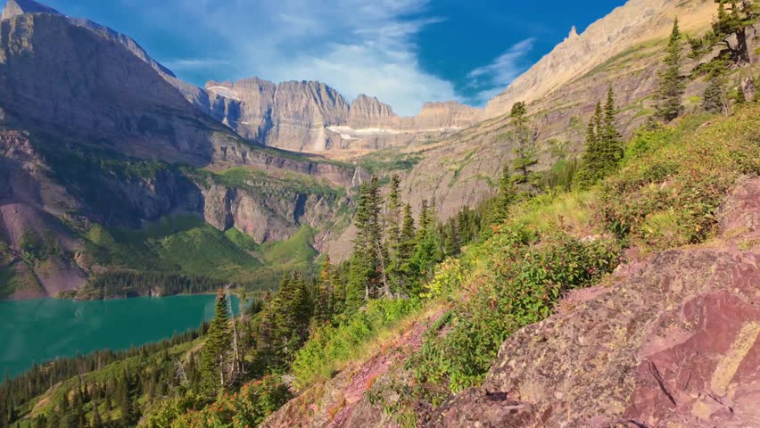 A scenic view of the turquoise Grinnell Lake seen from a hiking trail in the Many Glacier area of Glacier National Park