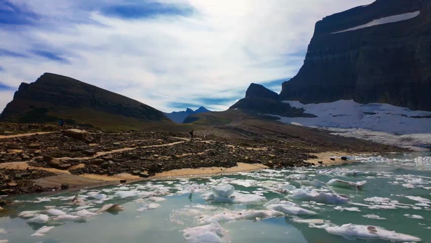 A stunning panoramic view of Upper Grinnell Lake with floating icebergs and the majestic Grinnell Glacier