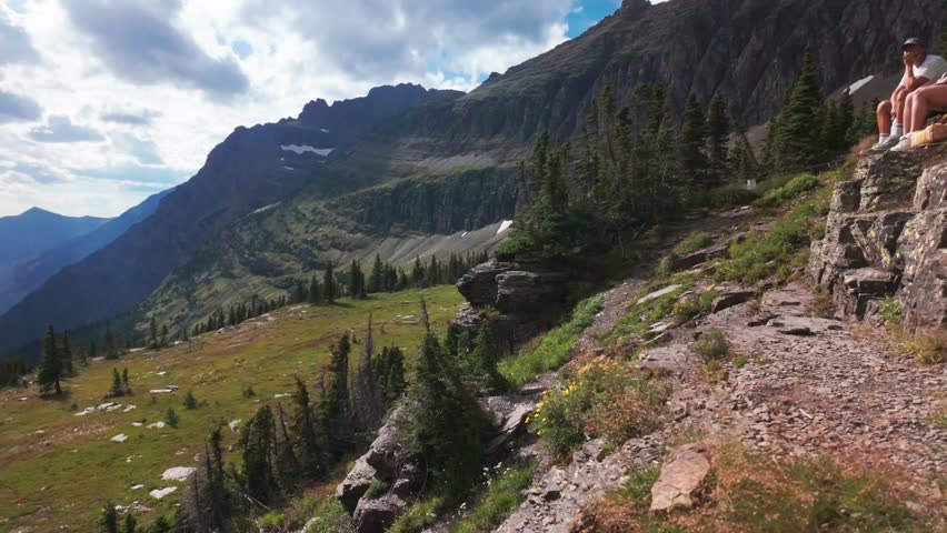 A panoramic view captures the serene Hidden Lake and its surrounding mountain range within Glacier National Park