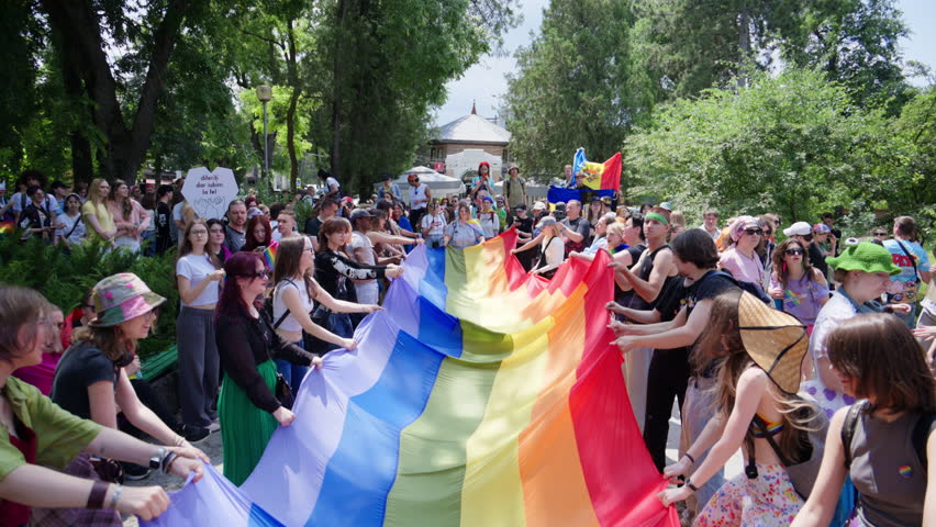 Chisinau, Moldova - June 15, 2025: Multiple people waving a long pride flag at the Pride March in the city center