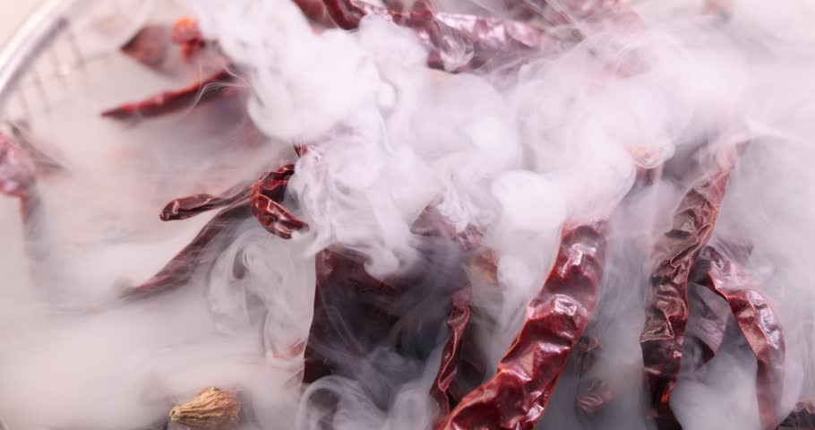 Red hot ripe chilli pepper flame smoke rising smoking raw dry on rustic table 