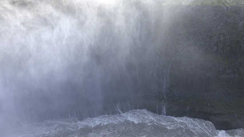 Detailed view of water thundering over the edge of Dettifoss, framed by rugged cliffs. The scene highlights the immense power and geological features of this dramatic Icelandic waterfall.