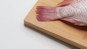 Side view One fresh Red Tilapia fish and Galangal, lemongrass, kaffir lime leaves on a wooden board - Powered by Shutterstock - Get 15% off with code: PIKWIZARD15