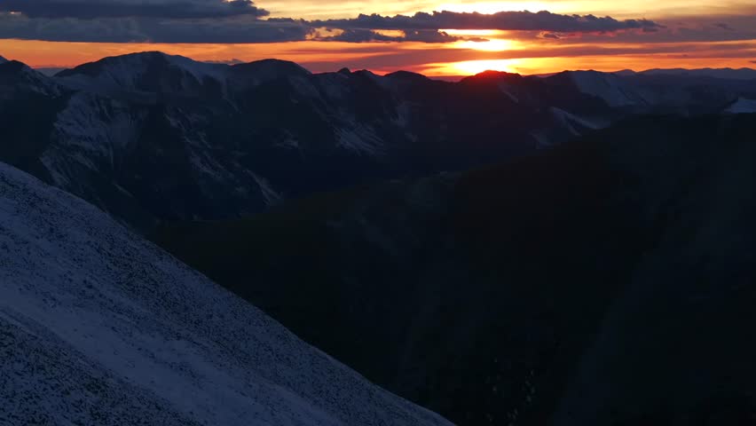 Glowing Rocky Mountains sunset Mt Mount Shavano Elbert Huron La Plata Tabeguache Antero Peak Colorado aerial drone fall autumn snow Sawatch Range top of summit sun on horizon clouds forward pan up