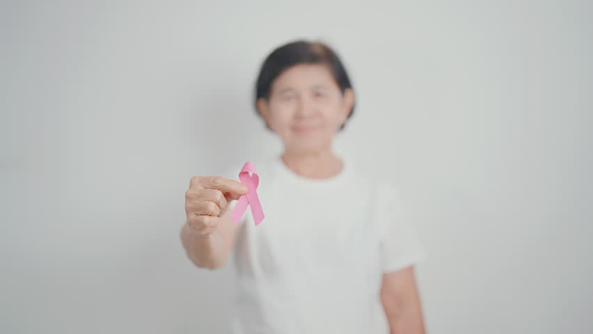 Elderly woman with pink Ribbon for Pink October Breast Cancer Awareness month, May Women Health, February World cancer day, support people life and illness. National cancer survivors month