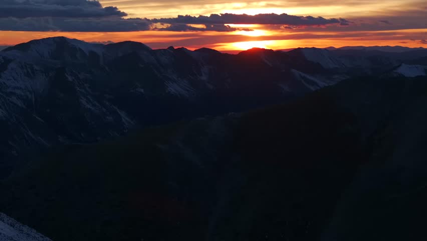 Glowing Rocky Mountains sunset Mt Mount Shavano Elbert Huron La Plata Tabeguache Antero Peak Colorado aerial drone fall autumn snow Sawatch Range top of summit sun on horizon clouds backwards pan up