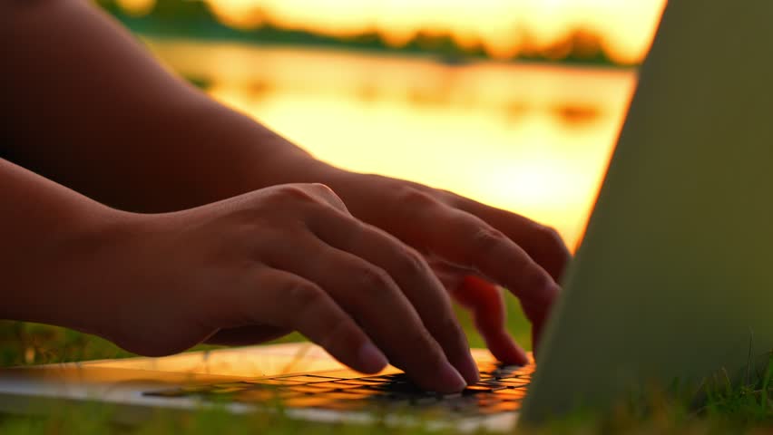Working on a laptop while sitting on the grass by a sunset lake shows remote work freedom, nature-inspired focus, digital nomad life, work-life balance, and creative relaxation.
 - Powered by Shutterstock - Get 15% off with code: PIKWIZARD15