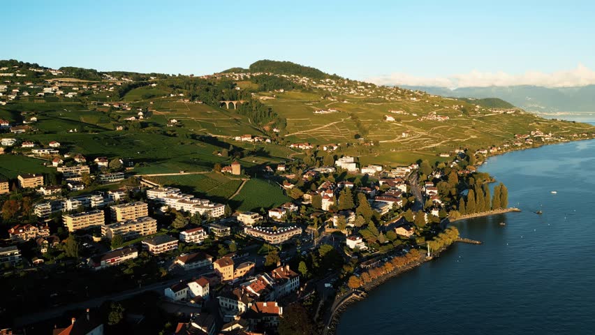 Aerial view of Lutry town nestled between vineyards and Lake Geneva, creating a beautiful contrast of green hills and blue waters, Lutry, Vaud, Switzerland.