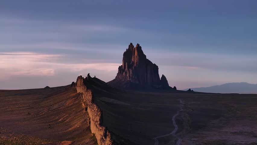 Aerial view of Shiprock Navajo peak stands as a majestic, towering monolith against the vast, arid landscape at dusk, Shiprock, New Mexico, United States.