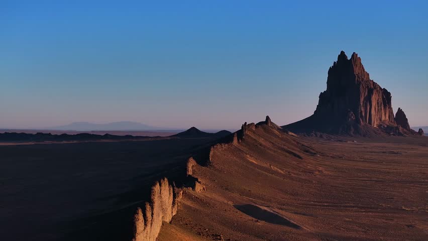 Aerial view of Shiprock Pinnacle, a majestic rock formation casting long shadows across the desert landscape, a geological wonder, Shiprock, New Mexico, United States.
