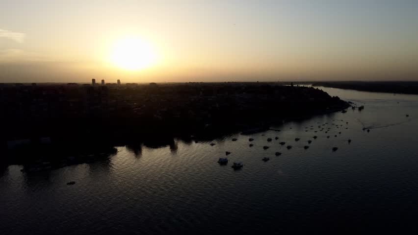 Aerial city shoreline at sunset with boats and urban skyline. g.