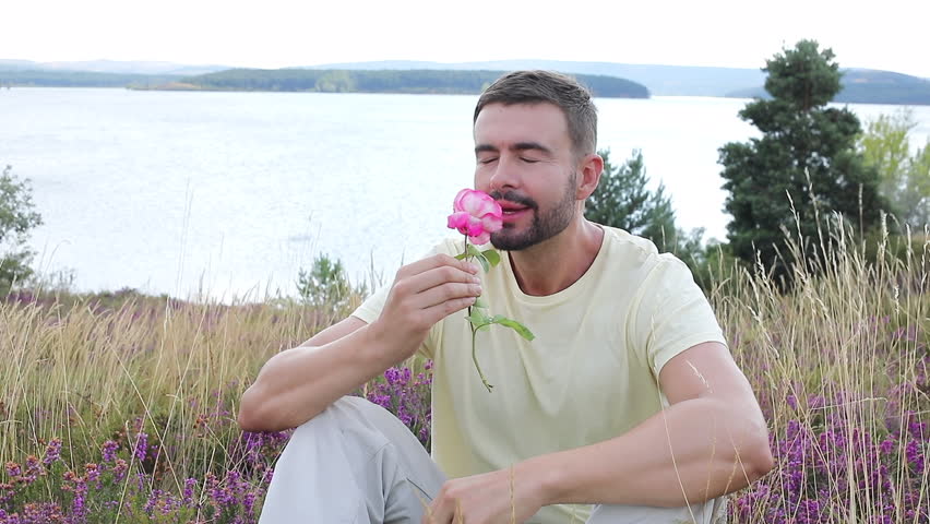 Man smelling a flower in stunning natural setting 