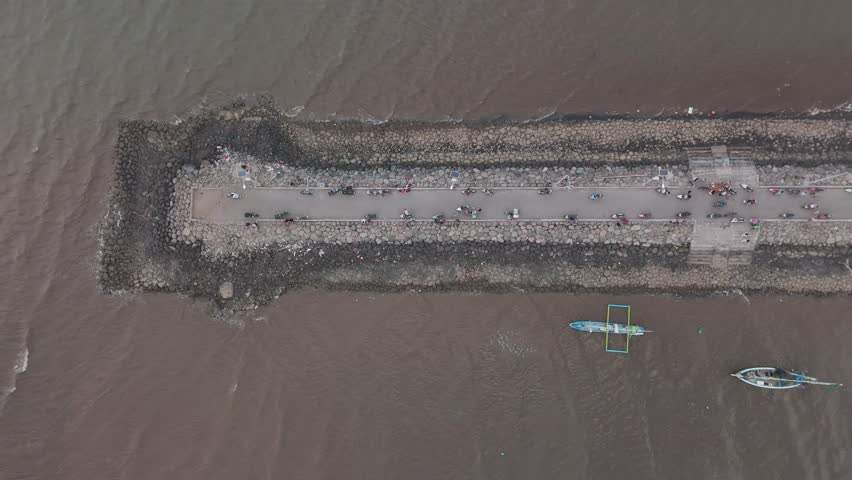 Aerial View of a Busy Coastal Road with Fishing Boats and Rocky Shoreline in the Background