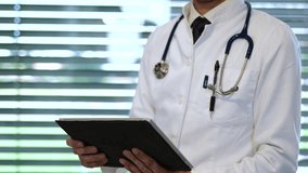 A close-up shot of a professional doctor interacting with a digital tablet, reviewing patient information in a modern medical office setting - Powered by Shutterstock - Get 15% off with code: PIKWIZARD15