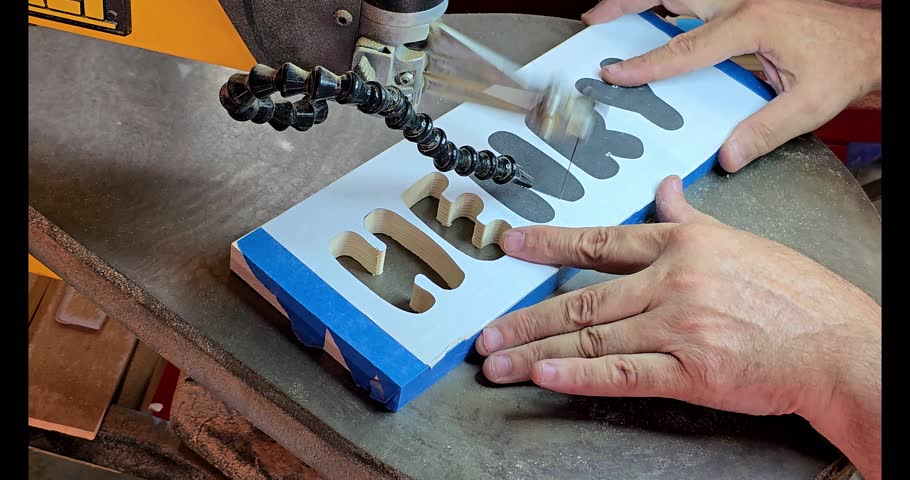 A 20 second video clip of a woodworker cutting letters out with a scroll saw.