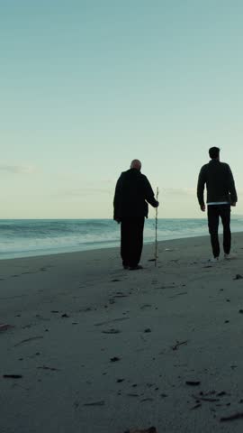 Silhouette Of Anonymous People Walking Towards Beach With Stormy Ocean Waves