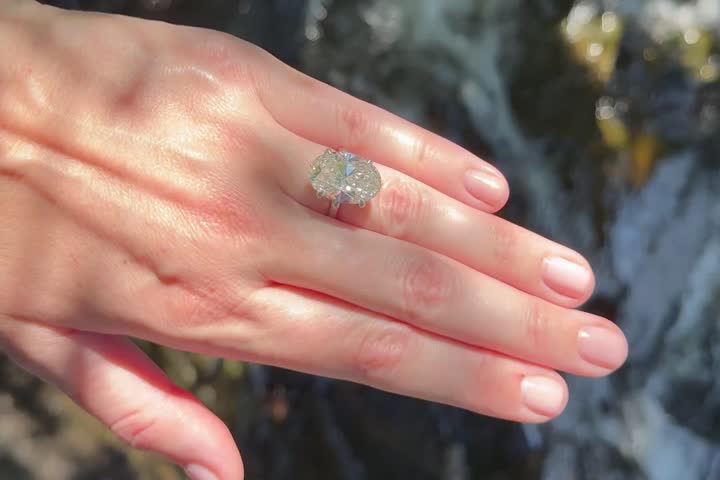 A landscape video showing a platinum engagement ring or wedding band with oval diamond catching natural light near a Swedish river with Scandinavian greenery.
