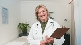 Confident Mature Female Doctor Smiling in Professional Medical Office Holding a Clipboard - Powered by Shutterstock - Get 15% off with code: PIKWIZARD15