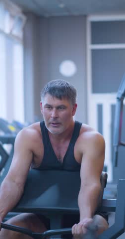 Gym workout. Bicep exercise. Middle aged Caucasian man trains his bicep muscles in the gym. Caucasian man performs bicep curls, dedicating effort to muscle growth during his gym workout.