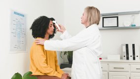 Senior Female Doctor Measures Temperature of Young Diverse Patient During a Medical Consultation - Powered by Shutterstock - Get 15% off with code: PIKWIZARD15