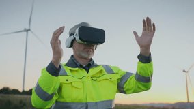 Engineer in high visibility jacket using VR headset outdoors. Man lifting both hands while interacting with virtual interface. Professional applying virtual reality at wind energy project site. - Powered by Shutterstock - Get 15% off with code: PIKWIZARD15