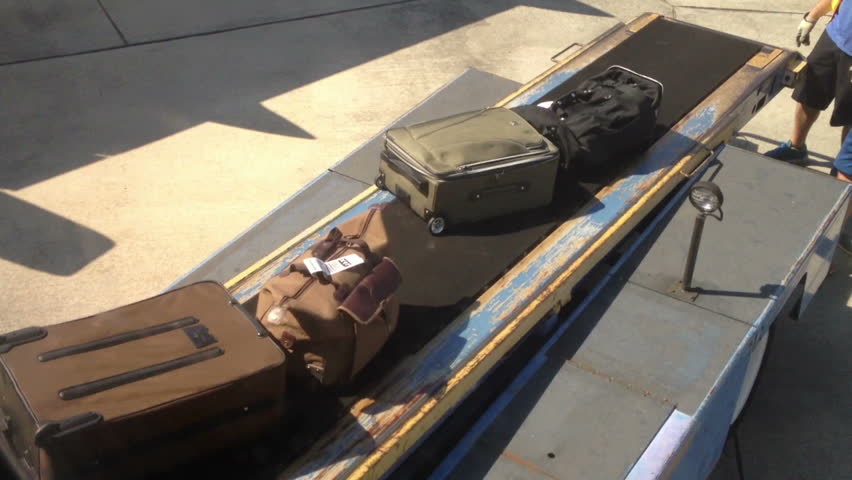 Baggage handlers remove bags from an airplane.
