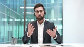 Webcam view. Confident businessman in headset talking on video call looking in camera sitting at workplace in office. Entrepreneur has a business meeting. Manager communicates at online conference - Powered by Shutterstock - Get 15% off with code: PIKWIZARD15