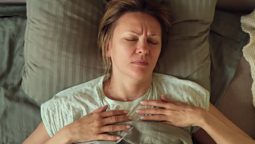 Close-up top view of mature 50s woman is turning in bed having nightmare trying to sleep. Tired Caucasian lady rolling at bedtime at home. Sleep deprivation, bad dream or nightmare